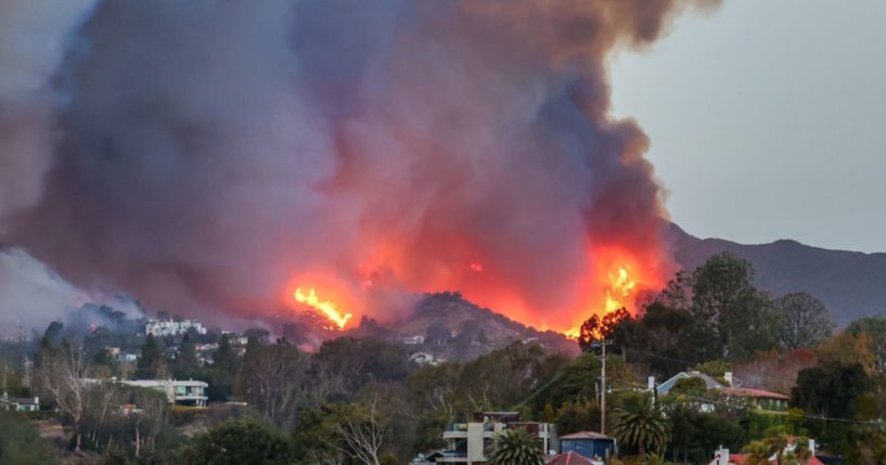 Smoke and flames from the Palisades Fire fill the sky as seen from the Pacific Palisades neighborhood of Los Angeles, California on January 7, 2025.