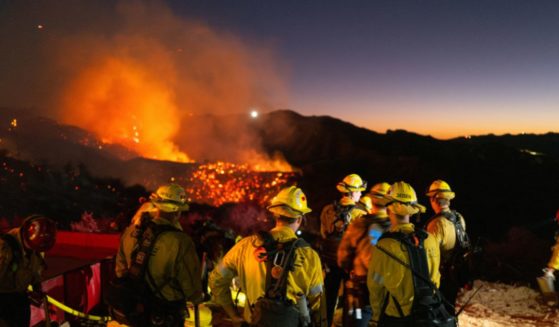 Firefighters work while smoke rises from the Palisades fire in Los Angeles, California, on Saturday.