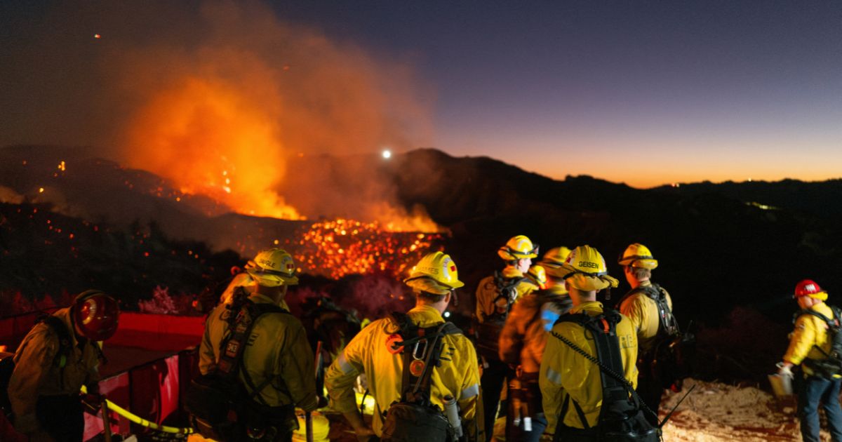 Firefighters work while smoke rises from the Palisades fire in Los Angeles, California, on Saturday.