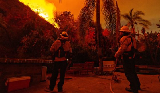 Firefighters stand guard at a home on Mandeville Canyon road as the Palisades fire spreads towards Encino on Saturday.