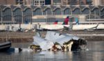 The U.S. Coast Guard investigates aircraft wreckage from Wednesday's aircraft collision on the Potomac River with Reagan National Airport in the background on Thursday.