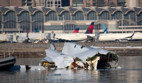 The U.S. Coast Guard investigates aircraft wreckage from Wednesday's aircraft collision on the Potomac River with Reagan National Airport in the background on Thursday.