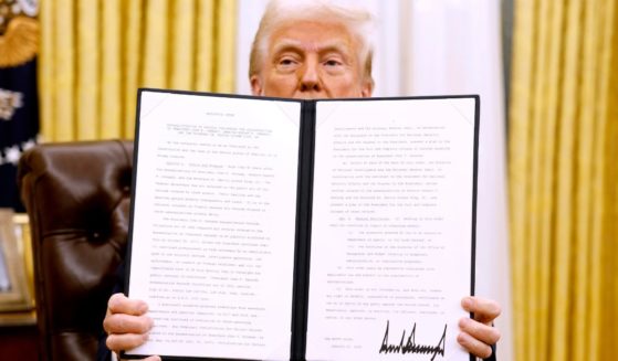 President Donald Trump holds up a signed executive order in the Oval Office of the White House on January 23, 2025, in Washington, D.C.