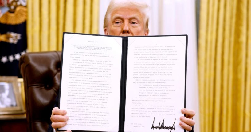 President Donald Trump holds up a signed executive order in the Oval Office of the White House on January 23, 2025, in Washington, D.C.