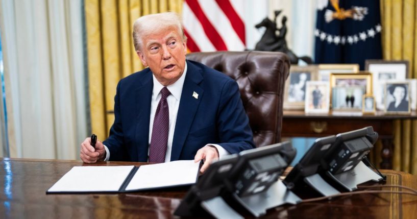 President Donald Trump speaks with reporters and signs executive orders in the Oval Office at the White House on in Washington, D.C.