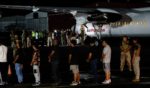 Ecuadorian migrants, with their hands and feet handcuffed, line up to climb a plane at the Albrook Gelabert airport in Panama City on August 29, 2024, during their deportation.