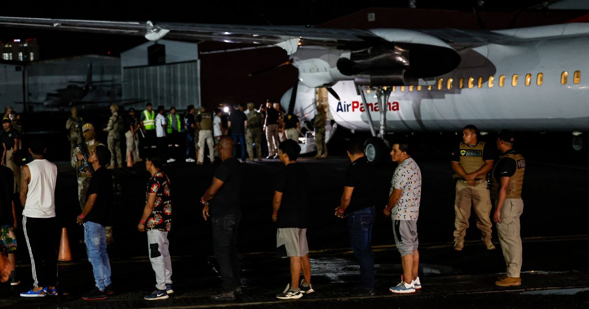 Ecuadorian migrants, with their hands and feet handcuffed, line up to climb a plane at the Albrook Gelabert airport in Panama City on August 29, 2024, during their deportation.