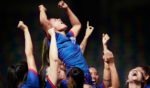 This stock image shows a women's soccer team celebrating a win.