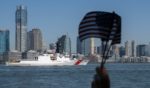 A person waves American Flags as the US Coast Guard passes during Fleet Week in New York Harbor on May 22, 2024.