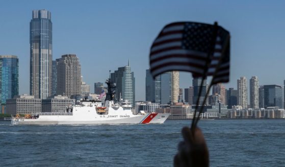 A person waves American Flags as the US Coast Guard passes during Fleet Week in New York Harbor on May 22, 2024.