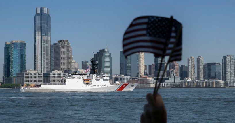 A person waves American Flags as the US Coast Guard passes during Fleet Week in New York Harbor on May 22, 2024.