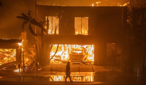 A firefighter watches the flames from the Palisades Fire burning homes on the Pacific Coast Highway amid a powerful windstorm on January 8, 2025 in Los Angeles, California.