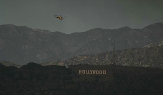 A firefighting helicopter flies above the Hollywood sign as the sky is engulfed in dark smoke from the many fires burning around the city, as seen from Kenneth Hahn State Recreation Area in Los Angeles, on January 8, 2025.