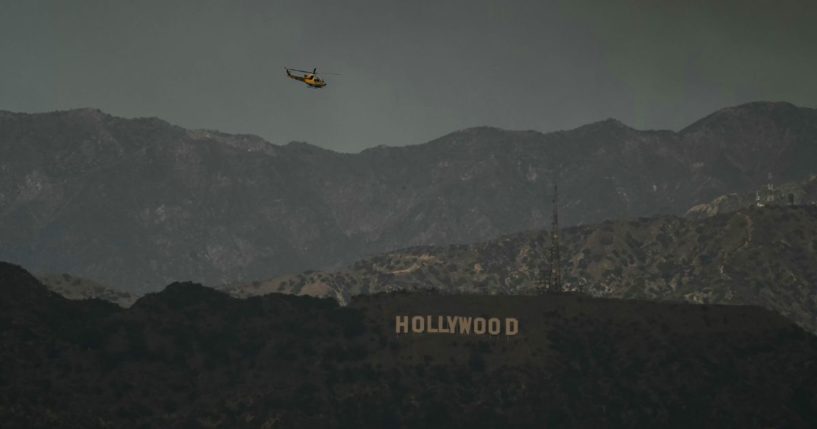 A firefighting helicopter flies above the Hollywood sign as the sky is engulfed in dark smoke from the many fires burning around the city, as seen from Kenneth Hahn State Recreation Area in Los Angeles, on January 8, 2025.