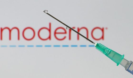 In this photo illustration, a syringe with a needle is seen in front of the Moderna logo on December 10, 2020 in Dortmund, Germany.