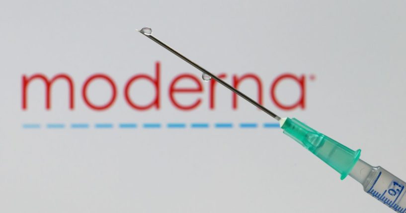 In this photo illustration, a syringe with a needle is seen in front of the Moderna logo on December 10, 2020 in Dortmund, Germany.