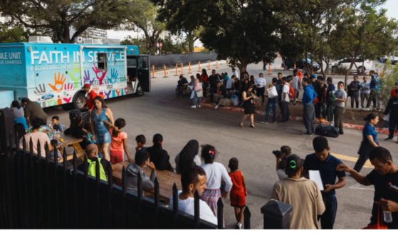 Groups of migrants wait outside the Migrant Resource Center in San Antonio, Texas, to receive food from the San Antonio Catholic Charities in a file photo from Sept.19, 2022.