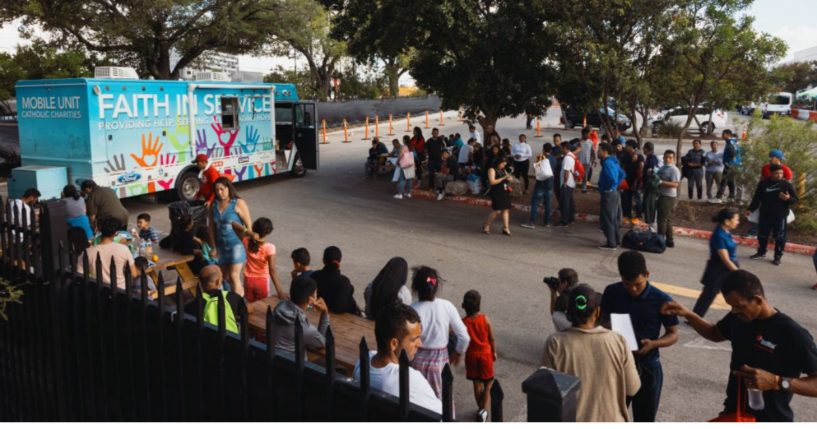 Groups of migrants wait outside the Migrant Resource Center in San Antonio, Texas, to receive food from the San Antonio Catholic Charities in a file photo from Sept.19, 2022.