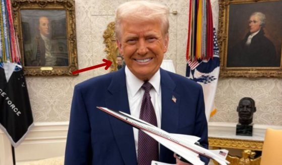 On Friday, President Donald Trump posed with a model of a supersonic jet, but some people noticed someone in the mirror behind him.