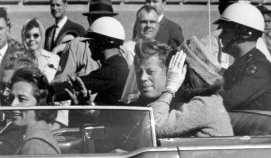 President John F. Kennedy waves from his car in a motorcade approximately one minute before he was shot in Dallas on Nov. 22, 1963. Riding with Kennedy are First Lady Jacqueline Kennedy, right, Nellie Connally, second from left, and her husband, Texas Gov. John Connally, far left.