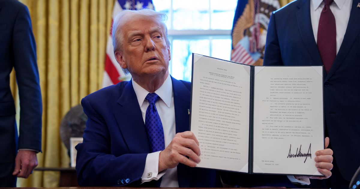 President Donald Trump signs an executive order withholding federal funding from schools and universities that impose a COVID-19 vaccine mandate in the Oval Office at the White House on Feb. 14, 2025, in Washington, D.C.