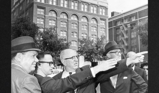 Members of the Warren Commission investigating the assassination of U.S. President John F. Kennedy, visited the scene in Dallas, Texas, Sept. 6, 1964. Looking over the site are, left to right, Louisiana Rep. Hale Boggs; Secret Service agent John Joe Howlett; Georgia Sen. Richard Russell and Kentucky Sen. John Sherman Cooper. In the background is the Texas School Book Depository Building from which, the commission determined -- some say erroneously -- the fatal shots were fired by a lone gunman.