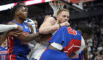 Minnesota Timberwolves guard Donte DiVincenzo, middle, and Detroit Pistons forward Ronald Holland II, right, fight during the first half of an NBA basketball game in Minneapolis on Sunday.