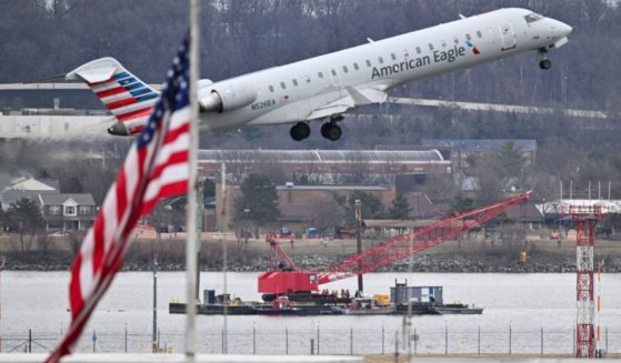 An American Eagle flight takes off Feb. 2 from Ronald Reagan Washington National Airport as a crane moves into position near airplane wreckage in the Potomac River. American Airlines flight 5342 collided with a U.S. Army military helicopter Jan. 29 in Arlington, Virginia, killing all 67 people aboard the two aircraft.