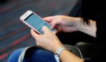 A woman uses her smartphone while waiting to board a plane at the Dallas/Fort Worth International Airport, located roughly halfway between Dallas and Fort Worth, Texas.