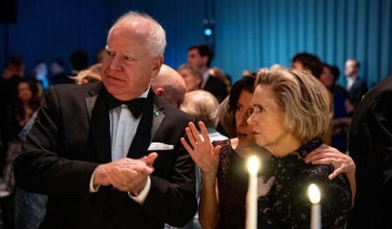U.S. Commerce Secretary Gina Raimondo (C) speaks with former Democratic vice presidential nominee, Minnesota Gov. Tim Walz (L) and his wife, Minnesota first lady Gwen Walz (R), during a dinner on the South Lawn of the White House on November 22, 2024 in Washington, DC.