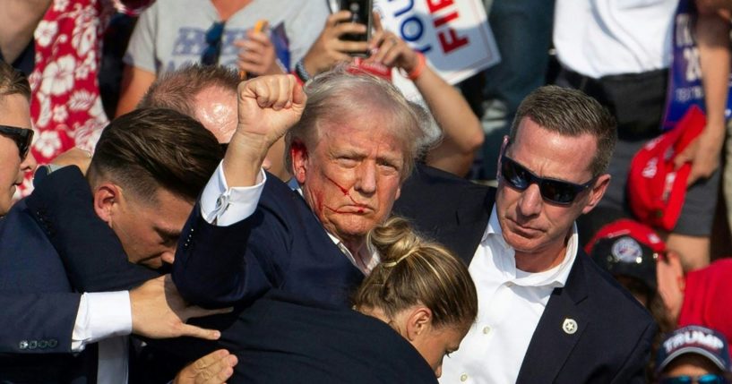 President Donald Trump is seen with blood on his face surrounded by Secret Service agents as he is taken off the stage at a campaign event in Butler, Pennsylvania, on July 13, 2024.