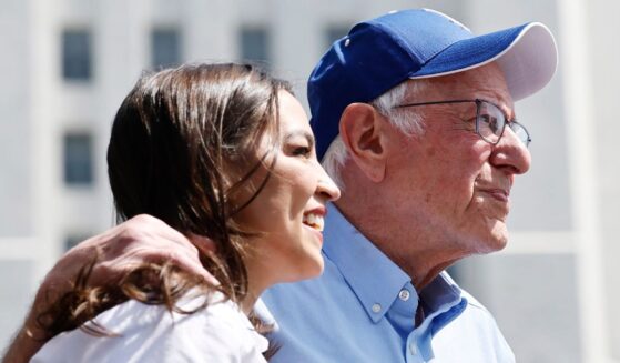 Sen. Bernie Sanders and Rep. Alexandria Ocasio-Cortez look toward the crowd during a stop on their "Fighting Oligarchy" tour in Los Angeles, California, on April 12.