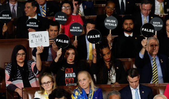 Democratic lawmakers hold up signs of protests as President Donald Trump addressed a joint session off Congress in Washington, D.C., on March 4.