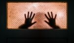 This stock image depicts a person trapped and pressing against glass, implying a human smuggling victim.